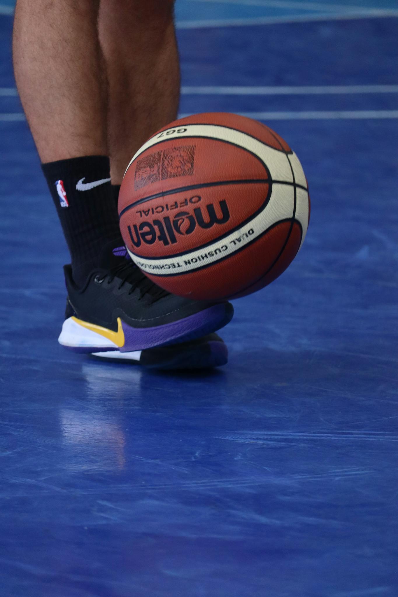 Close-up of basketball player's legs dribbling on an indoor court with a Molten ball.