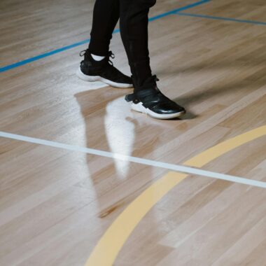Stylish black sneakers on a polished indoor basketball court floor.