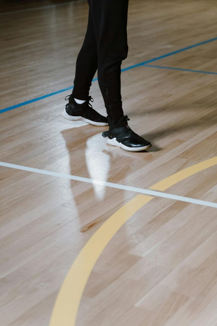 Stylish black sneakers on a polished indoor basketball court floor.